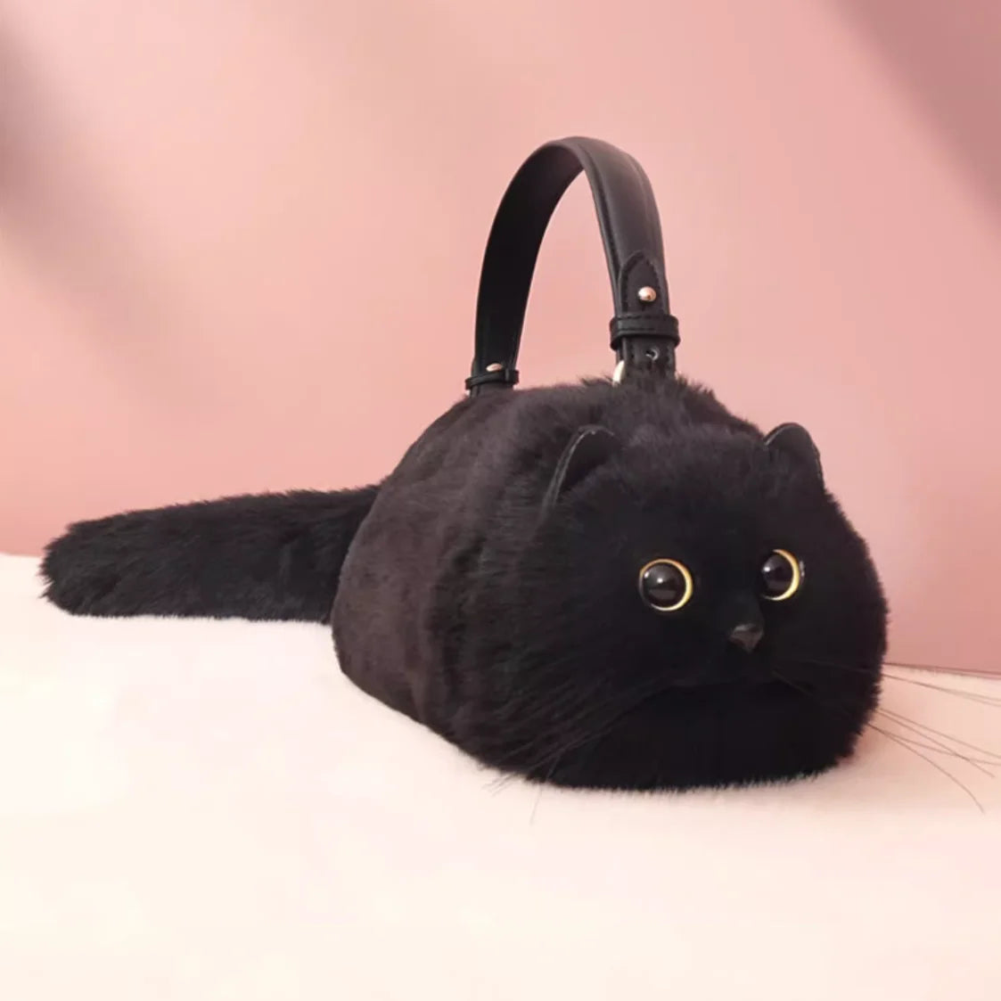 Black cat-shaped handbag on a pink background