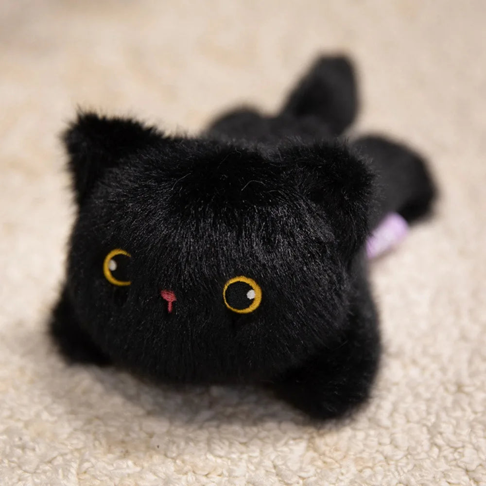 Black plush cat toy with yellow eyes and a pink nose on a beige carpet