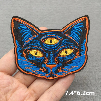 Embroidered patch of a cat's face held in a hand with a gray background