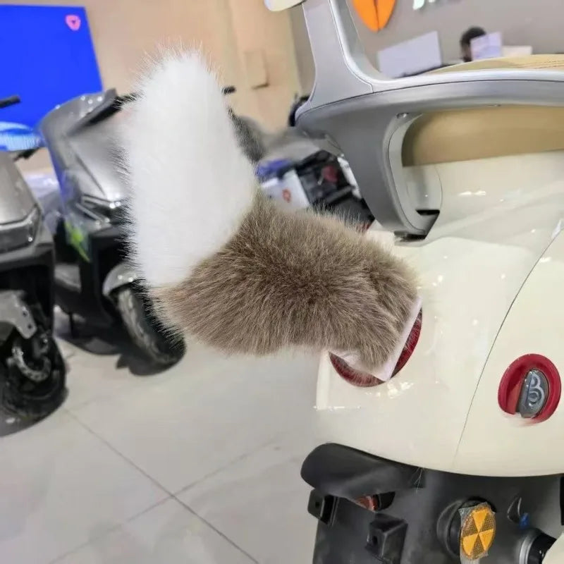Close-up of a scooter with a fluffy gray and white tail-like object attached, in an indoor setting.