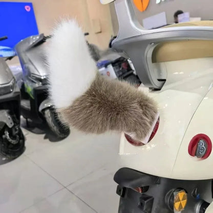 Close-up of a scooter with a fluffy gray and white tail-like object attached, in an indoor setting.