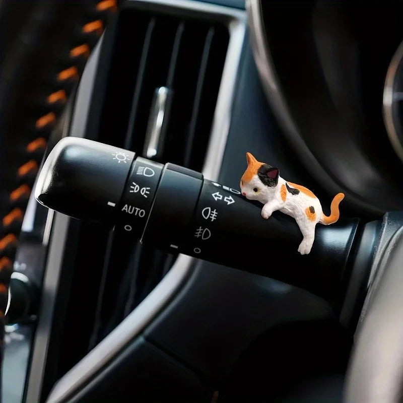 Car air vent with a decorative cat figurine on a black panel