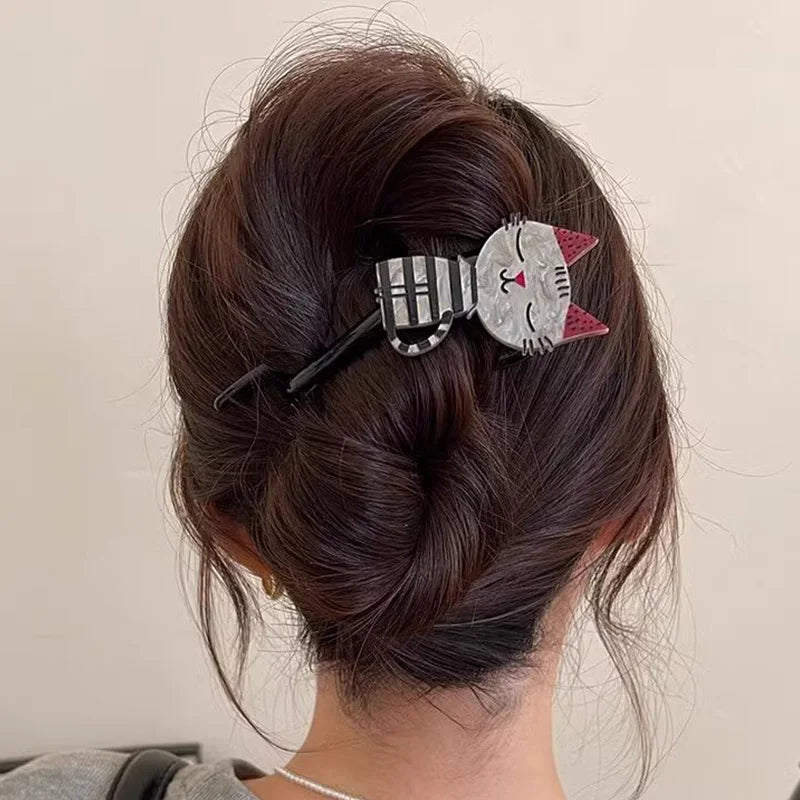 Cat-shaped hair clip in a person's hair against a neutral background