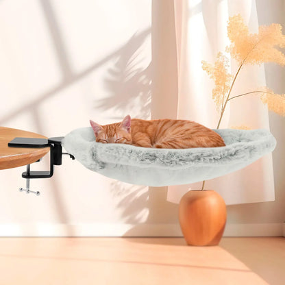Cat resting on a marble-patterned cat shelf attached to a table with a soft focus background