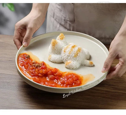 A hand lifting a cat-shaped sushi cooking mold off a piece of shaped sushi rice on a black surface, demonstrating the use of the mold.