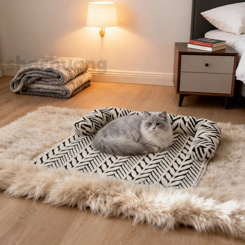 Cat lying on a patterned pet bed in a bedroom with a lamp and books in the background.