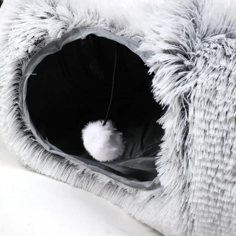 Close-up of a fluffy pet bed with a white pom-pom toy inside.