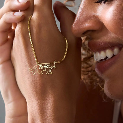 Gold necklace with 'Bella' pendant on a person's wrist, smiling.