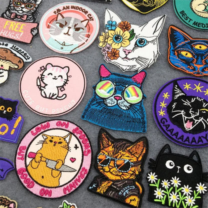 Collection of colorful cat-themed patches on a gray background