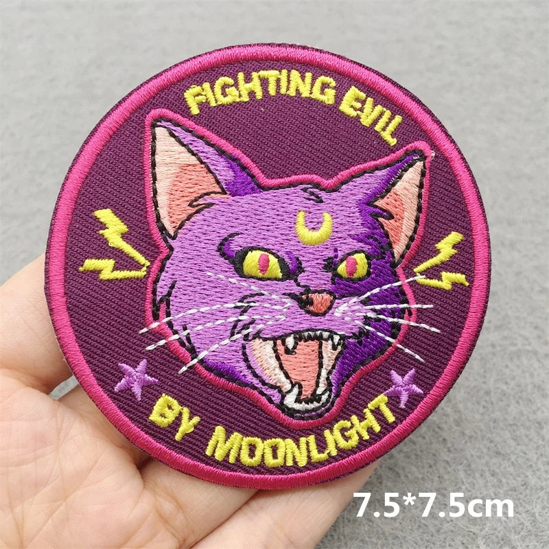 Embroidered patch with a purple cat design and text on a gray background