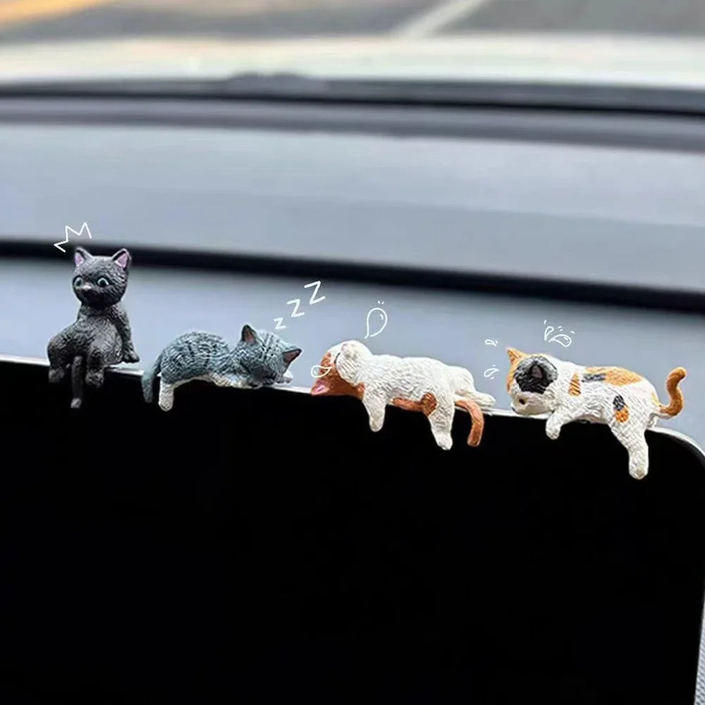 Five small cat figurines on a car's dashboard with cartoon-style illustrations above them.