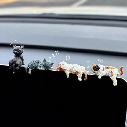Five small cat figurines on a car's dashboard with cartoon-style illustrations above them.