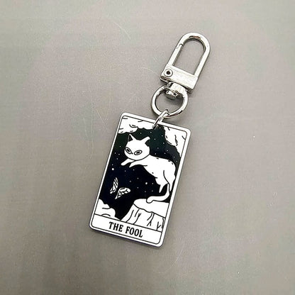 A collection of acrylic keychains featuring black and white tarot card designs with cat imagery.