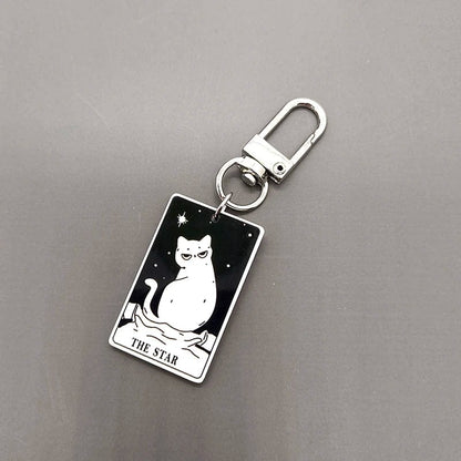 A collection of acrylic keychains featuring black and white tarot card designs with cat imagery.