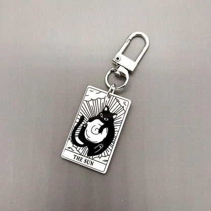 A collection of acrylic keychains featuring black and white tarot card designs with cat imagery.