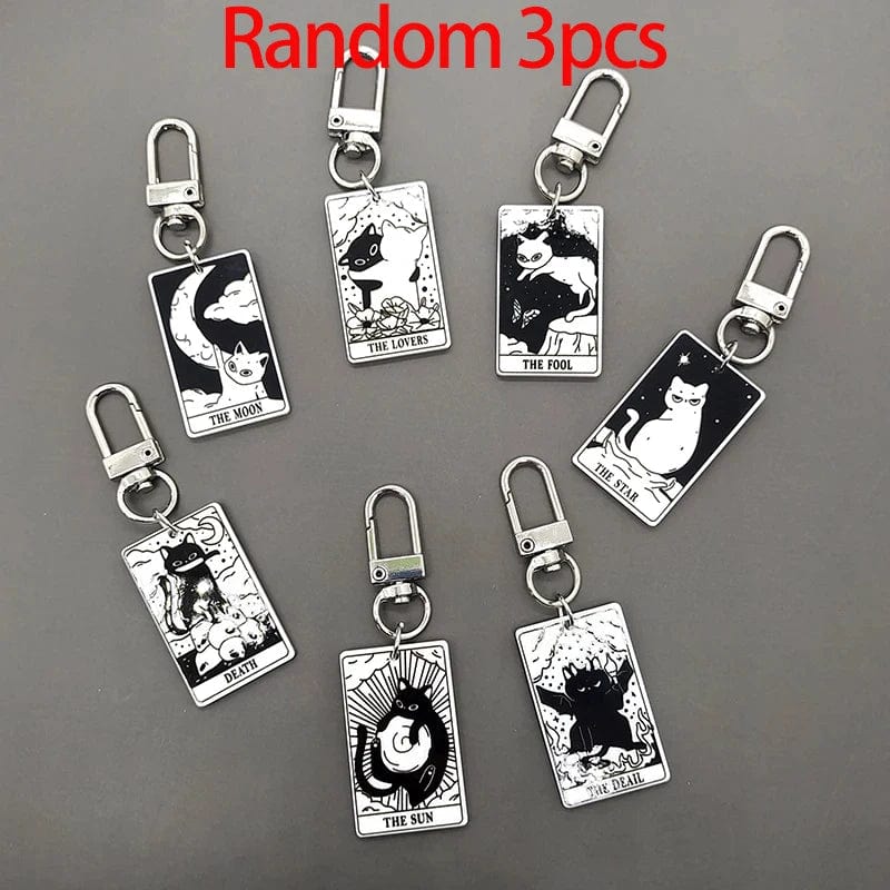 A collection of acrylic keychains featuring black and white tarot card designs with cat imagery.