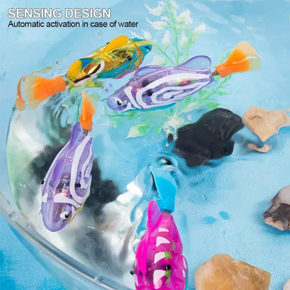 A selection of colorful cat electric fish water toys swimming in a bowl of water, with a white cat watching.