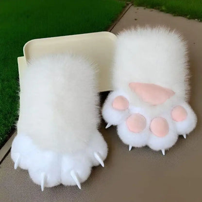 Pair of fluffy white paw-shaped gloves with pink pads on a green grass background