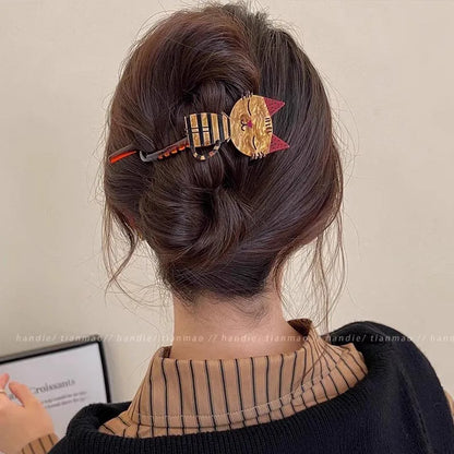 Person with a decorative hair clip in their bun, wearing a striped shirt and dark sweater.
