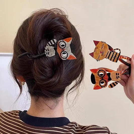 Person with a hair clip featuring a cat design, holding another similar clip.