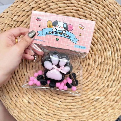 A hand holding a black and purple cat paw-shaped stress relief toy with a visible purple ribbon detail.