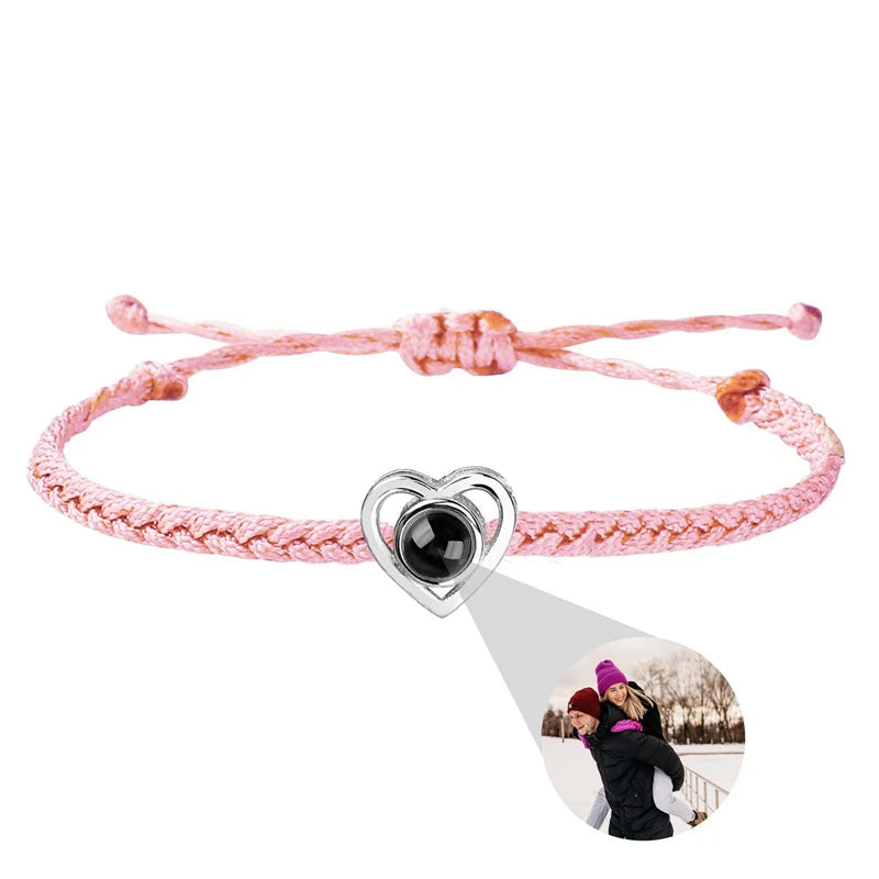 Pink braided bracelet with a heart-shaped charm featuring a photo of two people on a white background