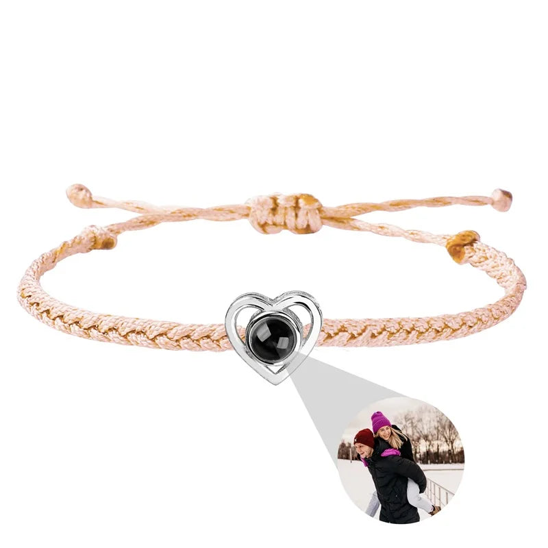 Pink braided bracelet with a heart-shaped charm featuring a photo of two people on a white background