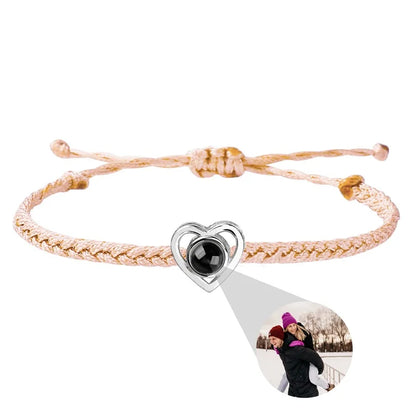 Pink braided bracelet with a heart-shaped charm featuring a photo of two people on a white background