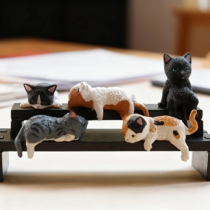 Set of cat figurines on a small platform with a blurred background