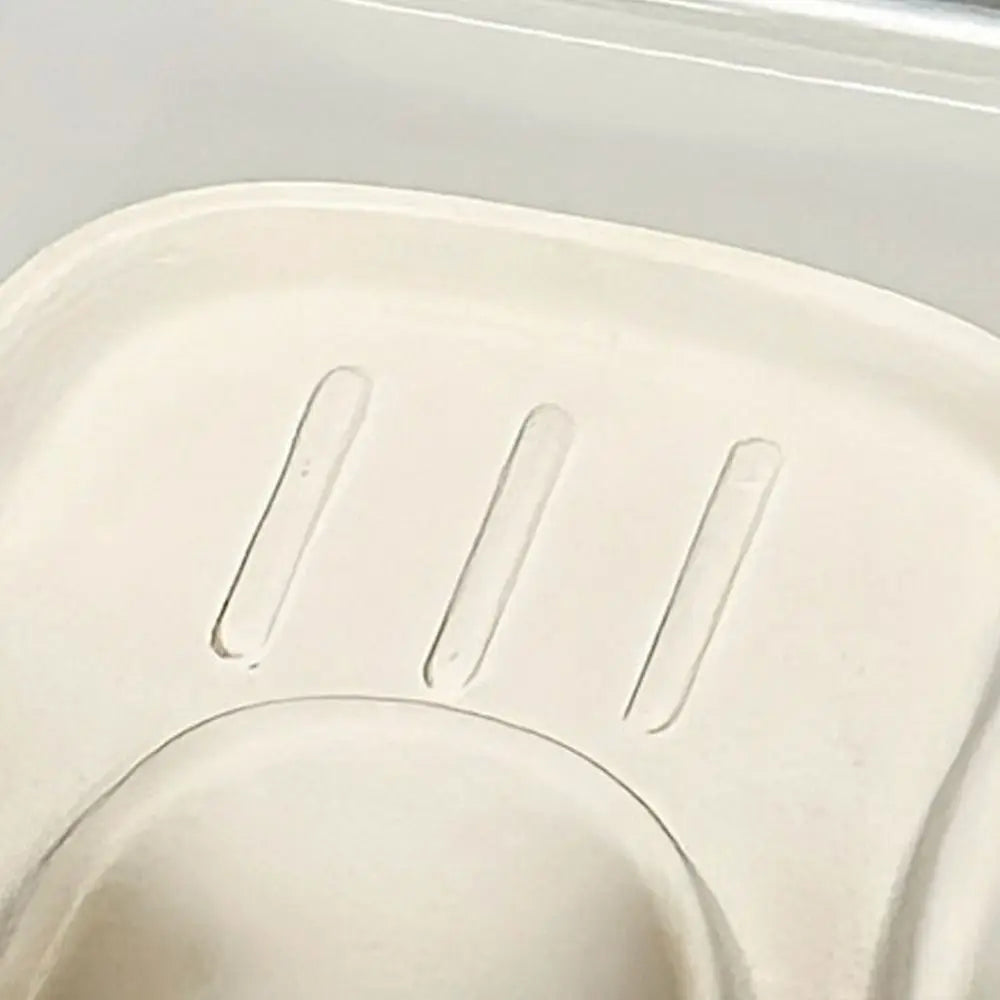 Close-up of a white plastic component with engraved lines on a light gray background