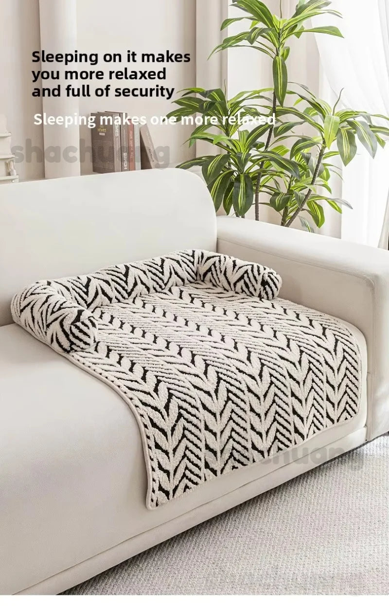 White sofa with a patterned throw blanket and a plant in the background.