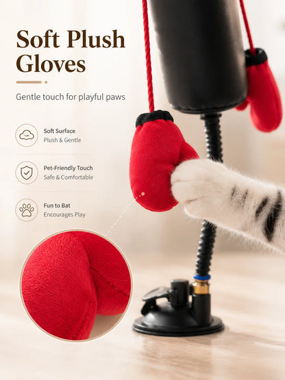 Red plush gloves with a black pump, used as a cat toy, on a light background.