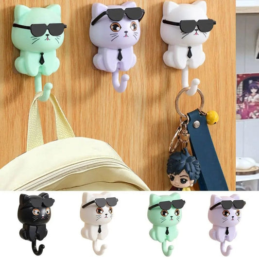 A collection of wall-mounted cat-shaped hooks in various colors, with the cats wearing sunglasses and ties, designed to hang items such as keys and bags.