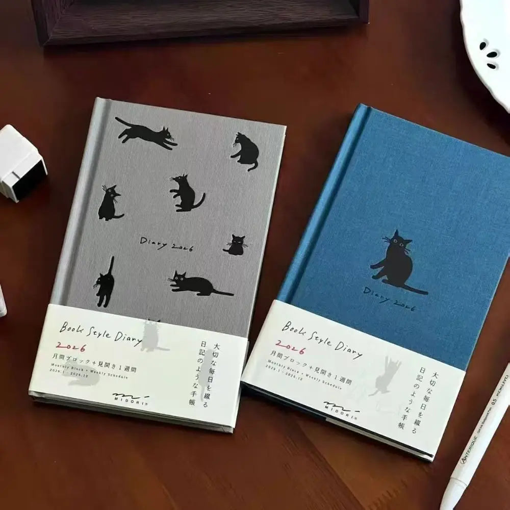 Two notebooks with cat illustrations on a wooden surface
