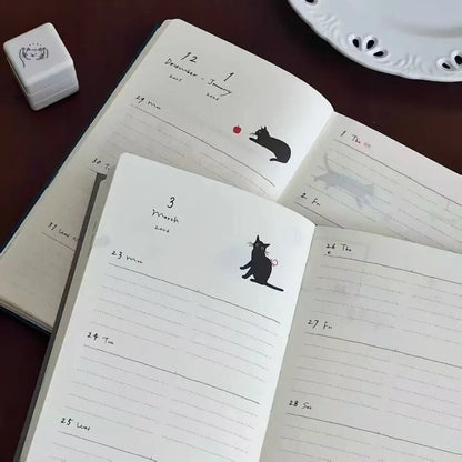 Open notebook with cat illustrations on a wooden surface