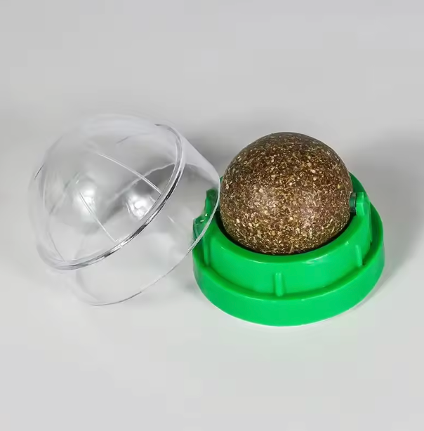 Green container with a clear lid and a gold-colored sphere inside on a white background