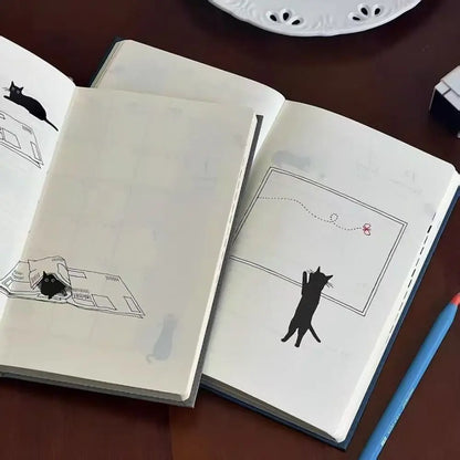 Open notebook with cat illustrations on a wooden surface