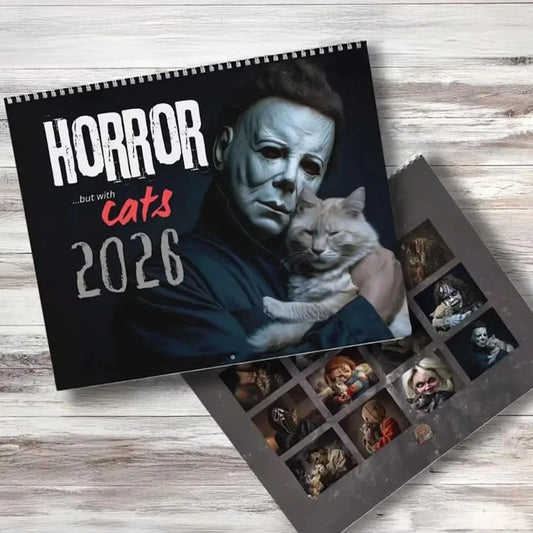 Calendar cover with a character holding a cat and text 'Horror... but with cats 2026' on a wooden surface.