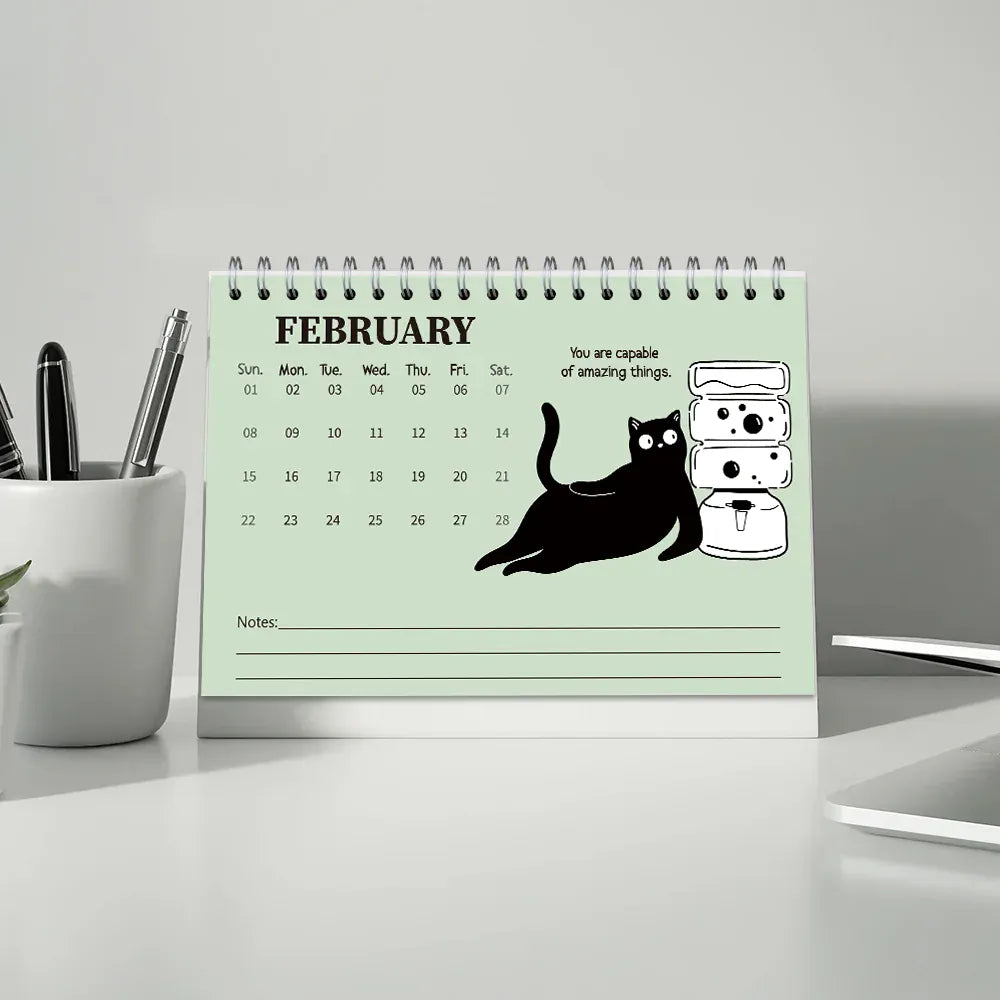 Desk calendar for February with a cat illustration and motivational quote on a light gray background.