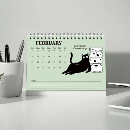 Desk calendar for February with a cat illustration and motivational quote on a light gray background.