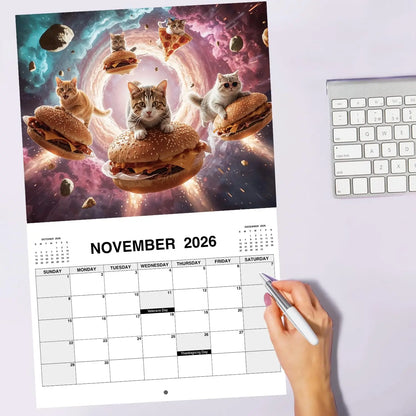 Calendar with a space-themed design featuring cats and food, held by a hand with a pen.
