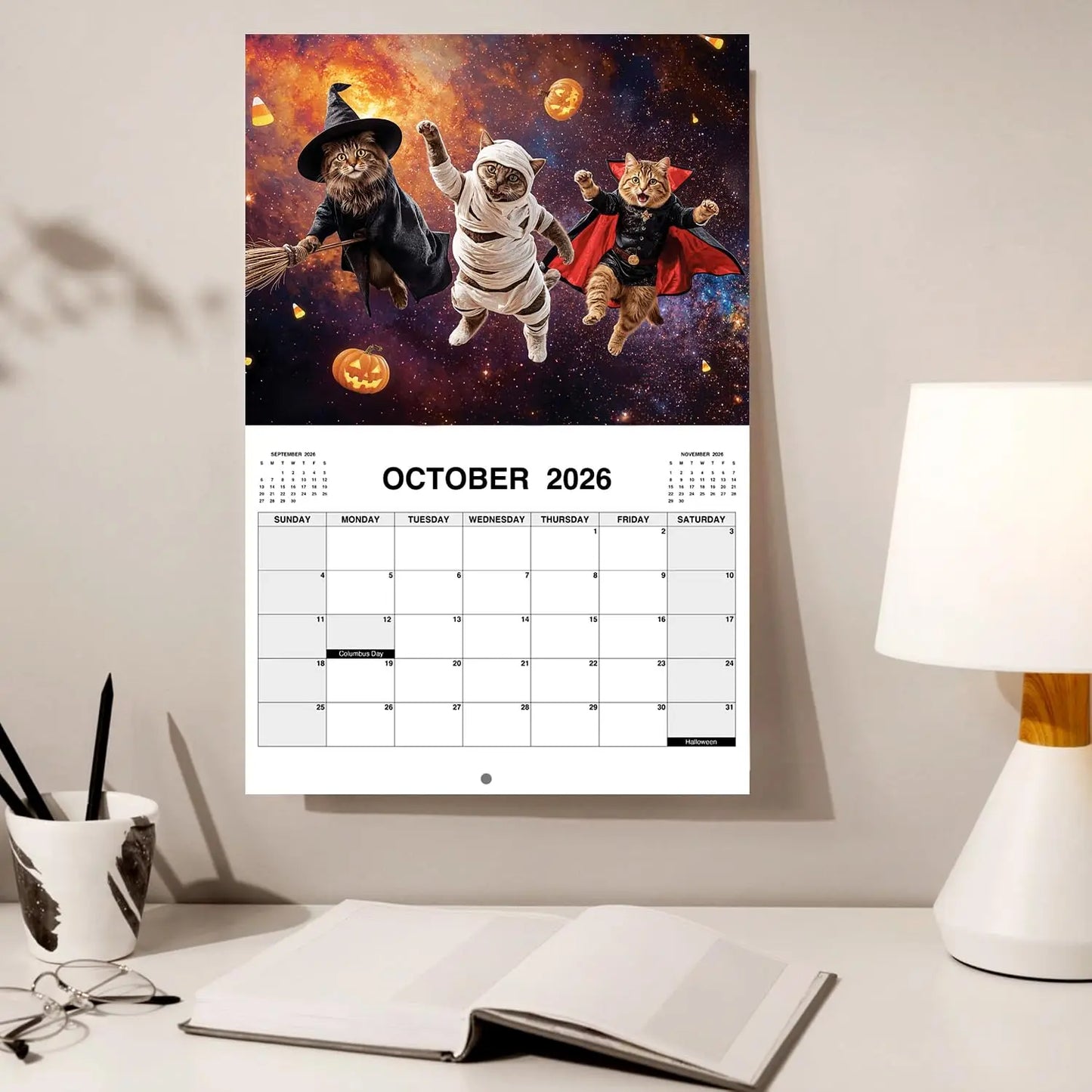 Calendar with Halloween-themed cats on a wall above a desk with office supplies.