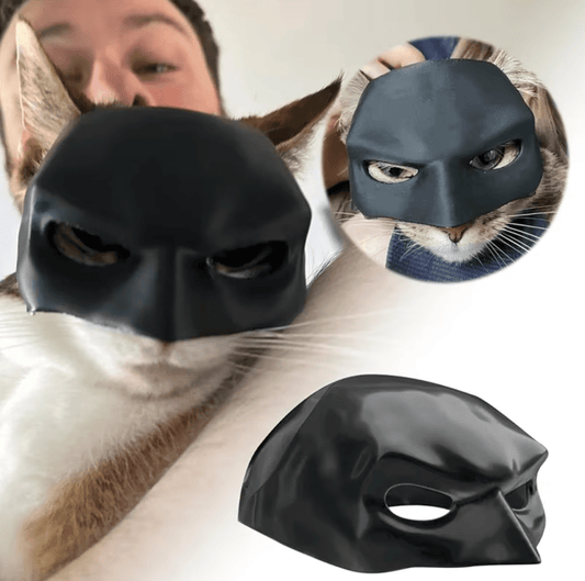 A black superhero mask designed for cats, with images showing the mask fitted on both a white and a black cat, as well as a human face for scale.